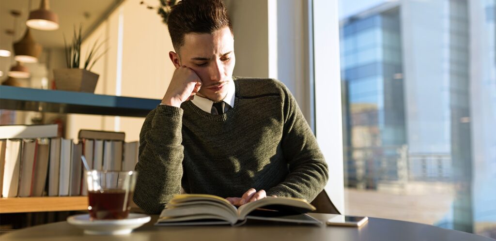 Homem vestido socialmente com um livro aberto sobre a mesa